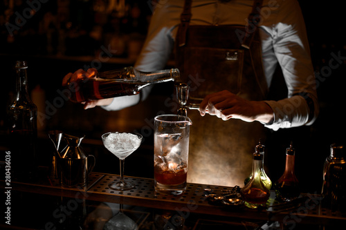 Bartender prepares alcohol cocktail using jigger with handle