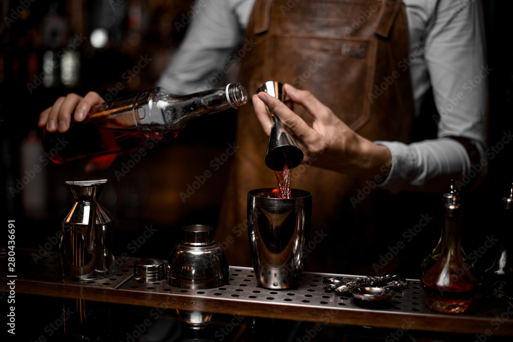 Close-up of bartender pouring alcohol from jigger to shaker
