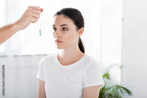 Photography cropped view of hypnotist holding green stone near woman