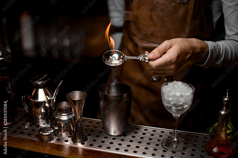 Bartender fires up alcohol in bar spoon