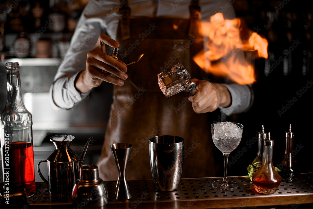 Bartender fires up an ice cube in tongs