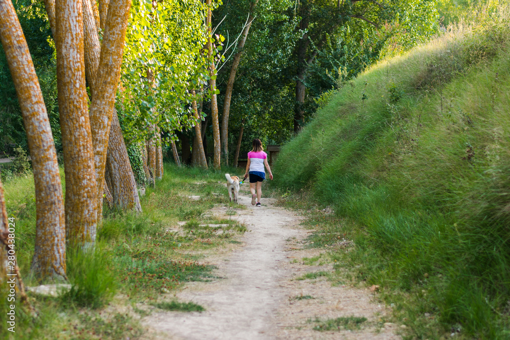 Middle-aged woman walking with her dog on a mountain path Middle-aged woman walking with her dog on a mountain path