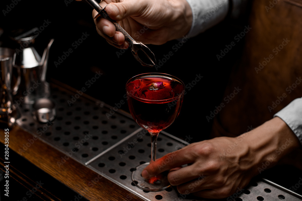 Bartender adds flower in an alcohol cocktail