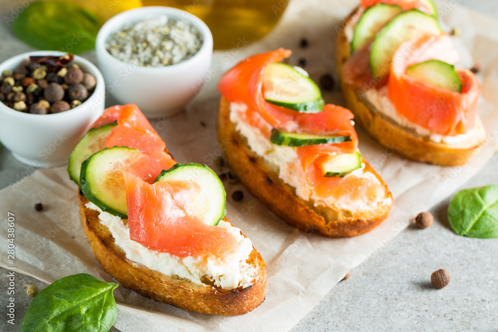 Salmon, cucumber and cream cheese bruschetta. Italian tapas, antipasti with vegetables, herbs and oil on grilled ciabatta and baguette bread. Sandwich. Salmon, cucumber and cream cheese bruschetta. Italian tapas, antipasti with vegetables, herbs and oil on grilled ciabatta and baguette bread. Sandwich.