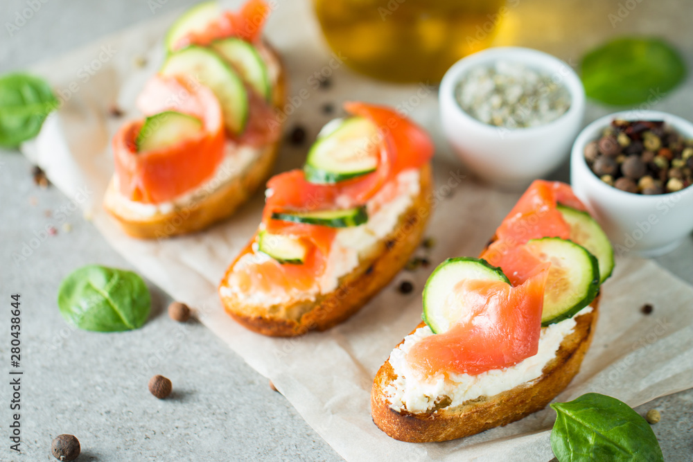 Salmon, cucumber and cream cheese bruschetta. Italian tapas, antipasti with vegetables, herbs and oil on grilled ciabatta and baguette bread. Sandwich.