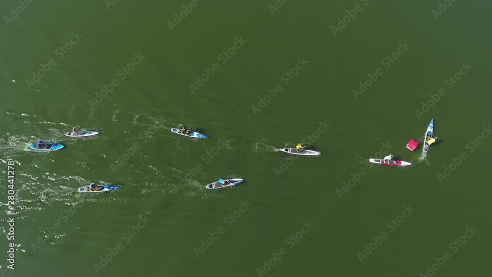 aerial top down of stand up paddle racers bypass buoy during water competition aerial top down of stand up paddle racers bypass buoy during water competition