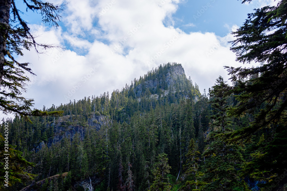 Fluffy white clouds over lone mountain peak in the Alpine Lakes Wilderness. Central Cascade Mountain Range, Washington State, July 2019. Fluffy white clouds over lone mountain peak in the Alpine Lakes Wilderness. Central Cascade Mountain Range, Washington State, July 2019.
