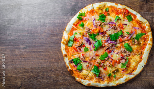 Pizza with Mozzarella cheese, onion, tuna fish, tomato sauce, pepper, basil. Italian pizza on wooden table background