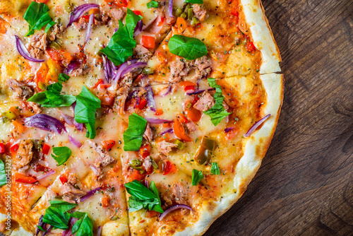 Pizza with Mozzarella cheese, onion, tuna fish, tomato sauce, pepper, basil. Italian pizza on wooden table background