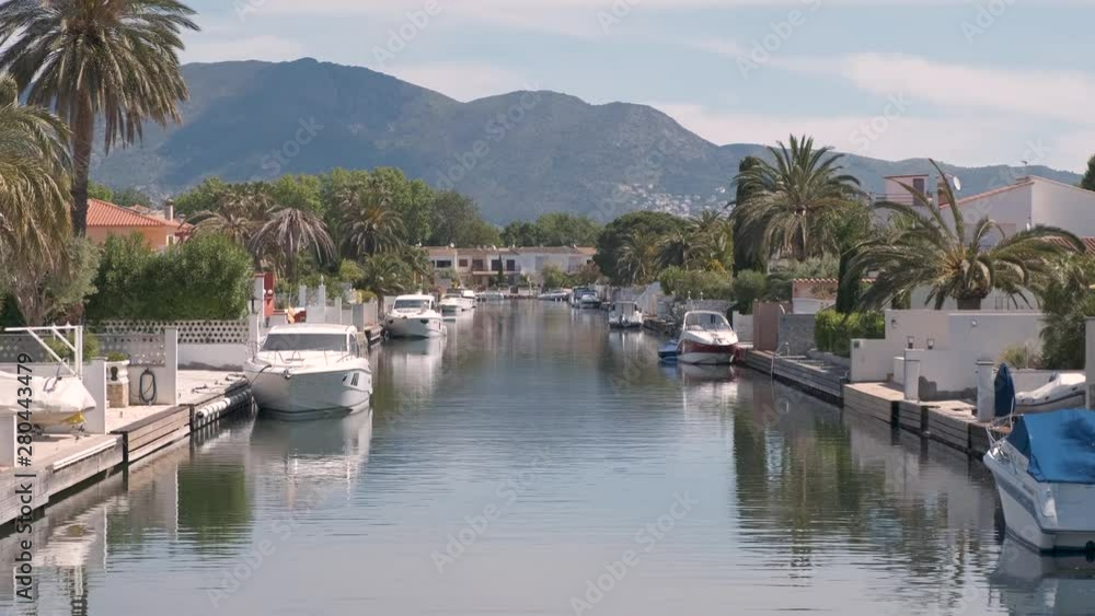 Amazing view on marine canal with boats and houses. Mooring of yachts near a house. Resort cityscape, palm trees, little Spanish Venice, Empuriabrava. Rich Perfect life. Summer, mountains, scenic view Amazing view on marine canal with boats and houses. Mooring of yachts near a house. Resort cityscape, palm trees, little Spanish Venice, Empuriabrava. Rich Perfect life. Summer, mountains, scenic view