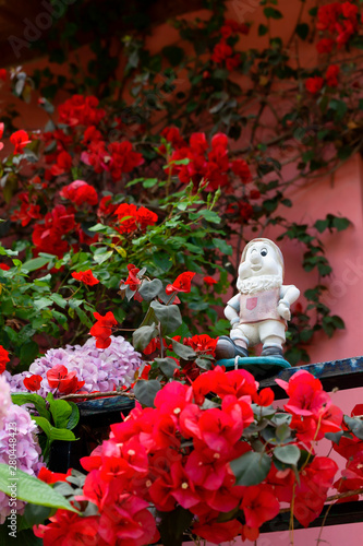 The figure of a plaster dwarf among the garden flowers