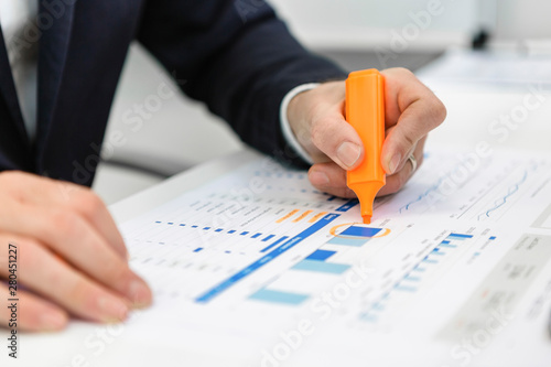 Close-up of businessman using highlighter on a report at desk in office photo