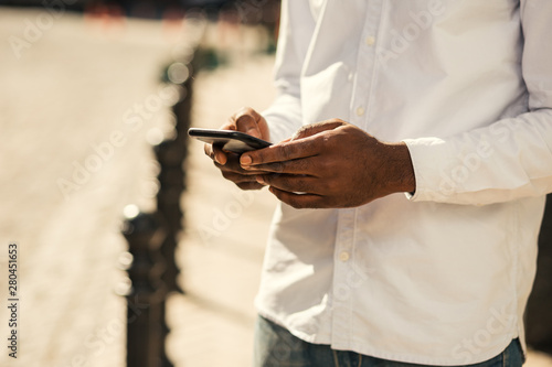 Hands of Afro American man holding modern smartphone