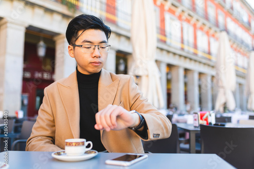 Spain, Madrid, young man checking the time in a cafe at Plaza Mayor photo