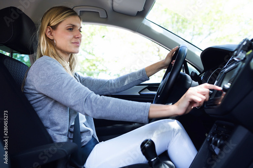 Young woman driver choosing a radio channel in her car photo