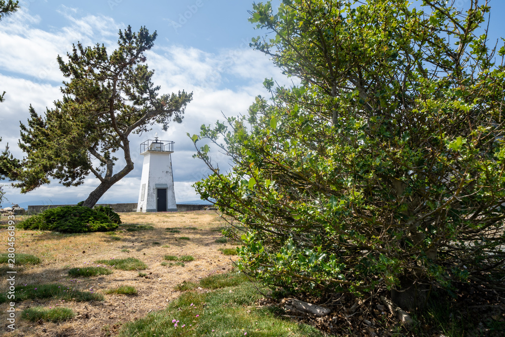 Bush Point Lighthouse, with trees framing the nautical structure on a summer day in Whidbey Island Washington