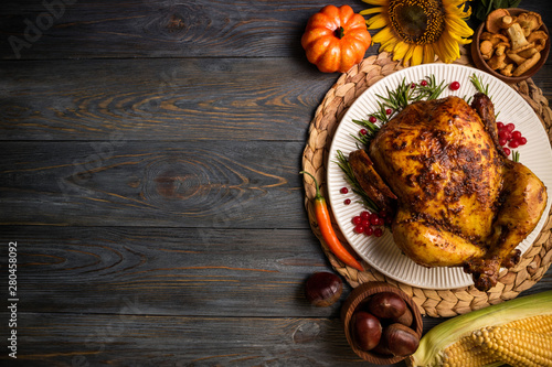 Roasted whole chicken or turkey with autumn vegetables for thanksgiving dinner on wooden background. Thanksgiving Day concept. Top view, copy space