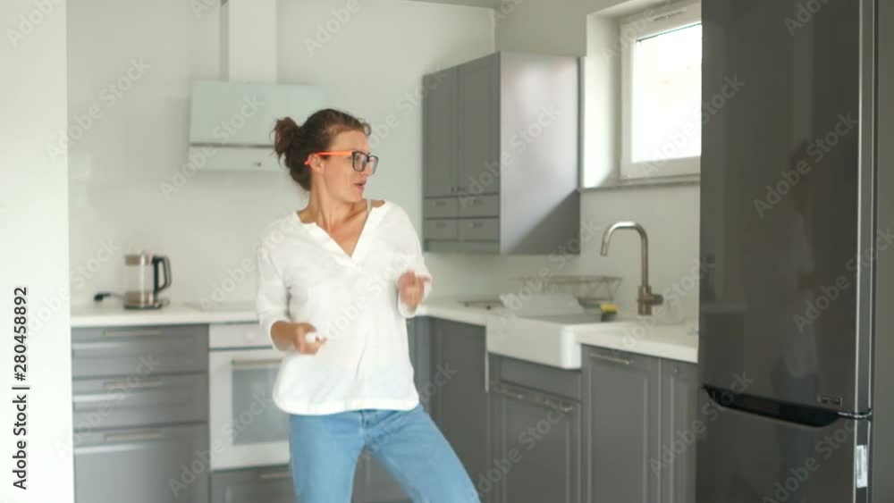 Portrait of a beautiful young woman dancing in her new kitchen after the renovation is completed. Real estate repair concept Portrait of a beautiful young woman dancing in her new kitchen after the renovation is completed. Real estate repair concept