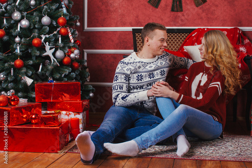 Young romantic cute couple staying at home and enjoying time together. Lovers hugging in cristmas decorated interior