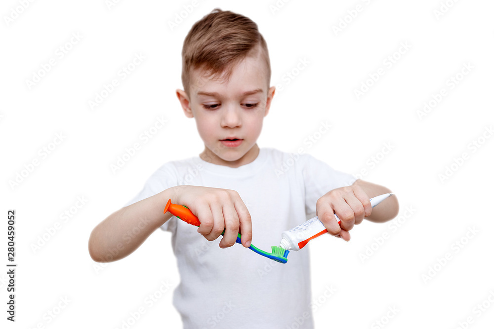 little boy in white t-shirt squeezes toothpaste on brush. Health care, hygiene and childhood concept. Caries prevention little boy in white t-shirt squeezes toothpaste on brush. Health care, hygiene and childhood concept. Caries prevention