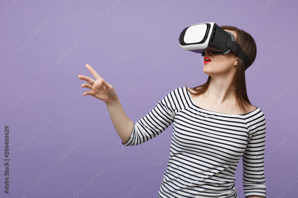 Young brunette woman girl in casual striped clothes posing isolated on violet purple background studio portrait. People sincere emotions lifestyle concept. Mock up copy space. Gesturing in vr headset. Young brunette woman girl in casual striped clothes posing isolated on violet purple background studio portrait. People sincere emotions lifestyle concept. Mock up copy space. Gesturing in vr headset.