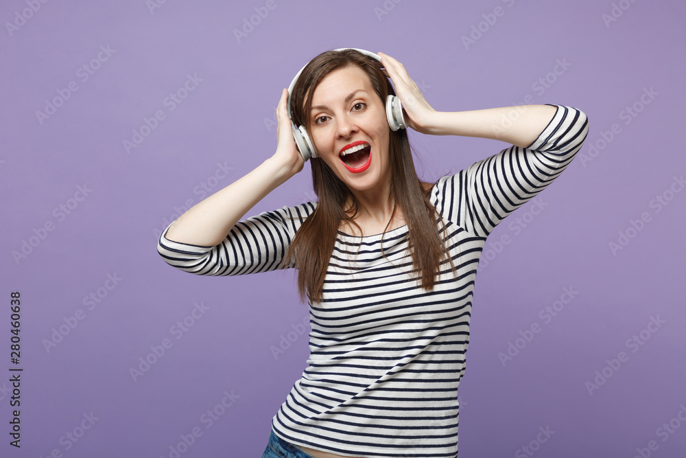 Young brunette woman girl in casual striped clothes posing isolated on violet purple background studio portrait. People sincere emotions lifestyle concept Mock up copy space Listen music in headphones Young brunette woman girl in casual striped clothes posing isolated on violet purple background studio portrait. People sincere emotions lifestyle concept Mock up copy space Listen music in headphones