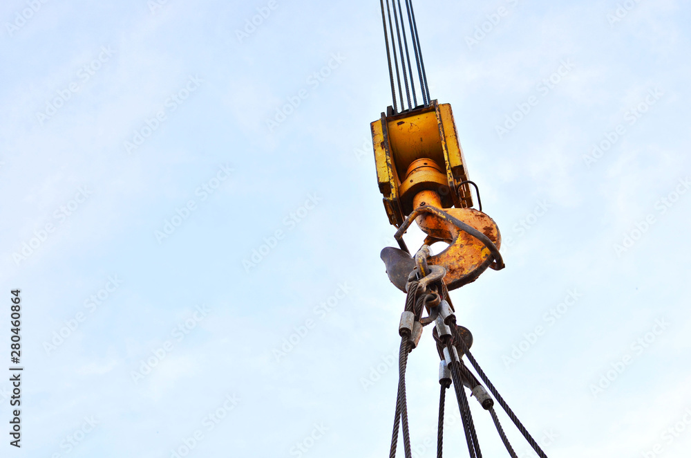 Large yellow crane hook on lifting fears and chains hanging on it for lifting loads on a background of blue sky. Construction concept - Image Large yellow crane hook on lifting fears and chains hanging on it for lifting loads on a background of blue sky. Construction concept - Image
