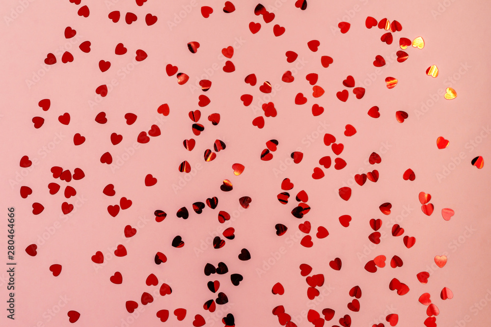 Red shining confetti in shape of heart on pink pastel background. Festive holiday backdrop for your designs and projects Red shining confetti in shape of heart on pink pastel background. Festive holiday backdrop for your designs and projects