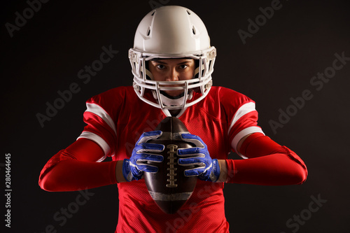 Image of american female football player in helmet with rugby ball in hands