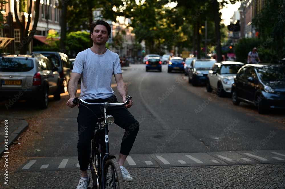 Spontaneous and happy young man riding a bicycle through an old street in Amsterdam, the Netherlands