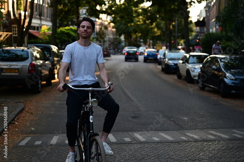 Spontaneous and happy young man riding a bicycle through an old street in Amsterdam, the Netherlands