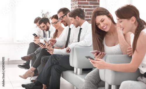 group of young people with gadgets sitting in the office reception