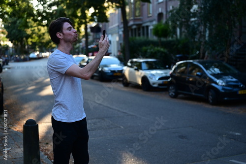 Spontaneous and loving young man giving his girlfriend a kiss on facetime while standing in the street  photo