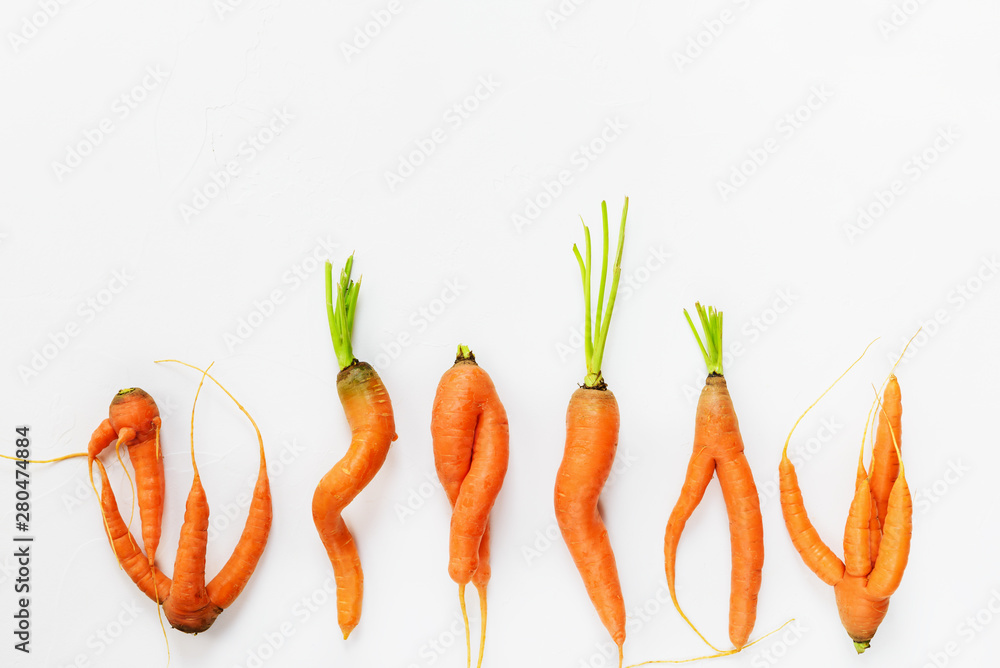 Ugly carrots on a white background. Ugly food concept, flat lay, copy space. - obrazy, fototapety, plakaty 