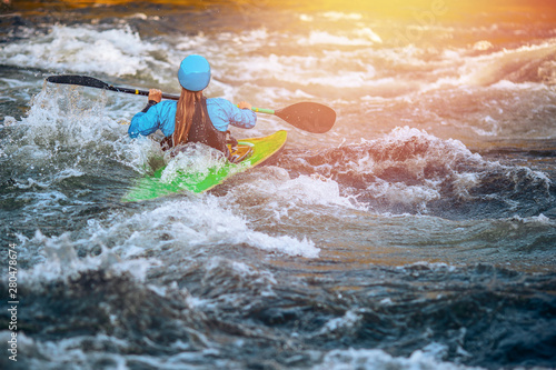 Girl in kayak sails mountain river. Whitewater kayaking, extreme sport rafting