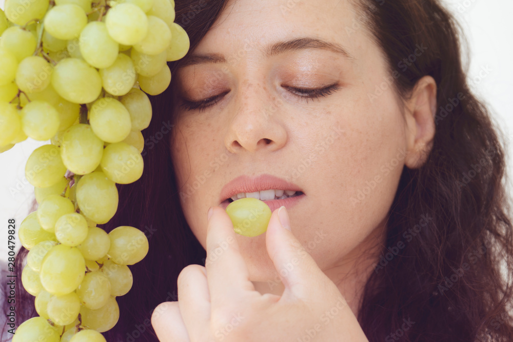 beautiful woman eating grapes is on the kitchen beautiful woman eating grapes is on the kitchen