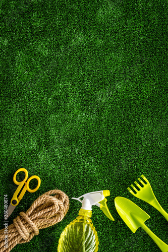 Gardening tools on green grass background top view copyspace