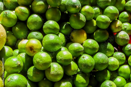 Street sale of green organic lemons, which the sunlight reaches strongly in Street market in Guanabano Bridge in La Baralt Aveneu, Caracas, Venezuela. photo