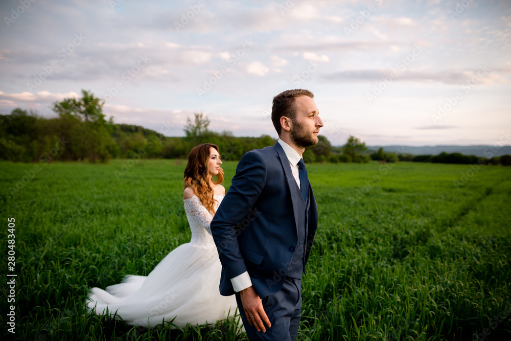 Wedding. Bride and groom holding hands and walk on the green field Wedding. Bride and groom holding hands and walk on the green field