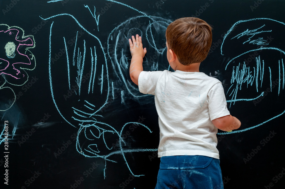 Small boy erasing with hand chalk drawing on blackboard