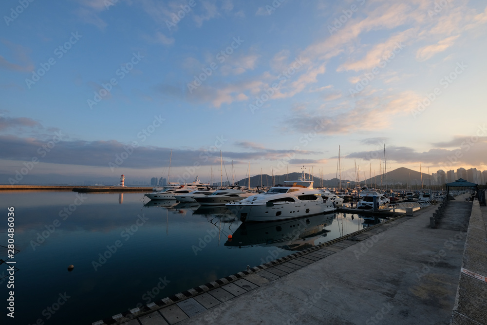 yachts marina at sunrise morning. beautiful sunny blue sky with white clouds. peaceful blue sea water. luxurious yachts berth in harbor. wide angle