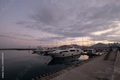 yachts marina at sunrise morning. wide angle. Beautiful purple cloudy sky. Peaceful sea water. Many luxurious yachts docked in harbor