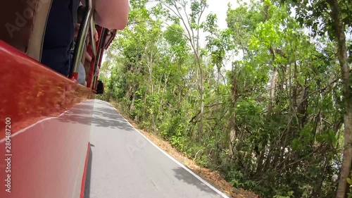 A tour bus rolls along a windy road, with a nice reflection in the paint making a mirror effect of a full roadway through the bus.  Segment 1of 4 in slow motion, one part of a longer clip photo