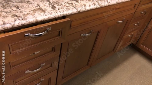 Prospective view of the kitchen cabinet drawer closing in slow motion. Kitchen cabinetry is made of maple natural wood and stained in red maple natural color photo