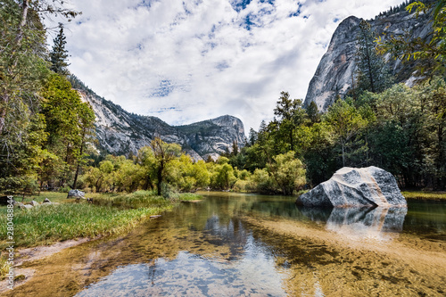 Scenic view of Mirror lake, along Tenaya Creek; surrounding mountain ridges reflected in the shallow, calm waters of the lake; Yosemite National Park, Sierra Nevada mountains, California