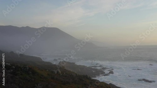 Dramatic aerial flying over ocean in Big Sur California at sunrise