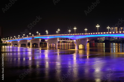 Long exposure of Yongjiang bridge in Nanning city Guangxi province China at night. Double cantilever reinforced concrete and Double column pier bridge. Purple reflection on river. Perspective