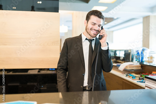 Handsome Clerk Accepting Accommodation Order On Phone In Hotel photo