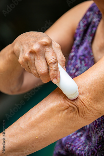 Fotografija Senior woman's right hand using muscle pain reliever roll her left elbow, Blue s