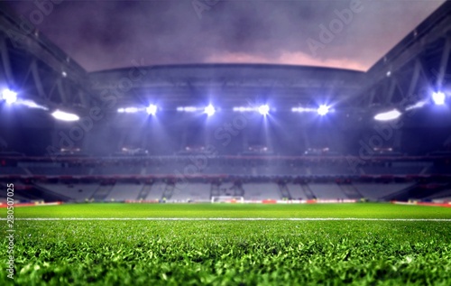 Stadium with green soccer field and bright spotlights at night